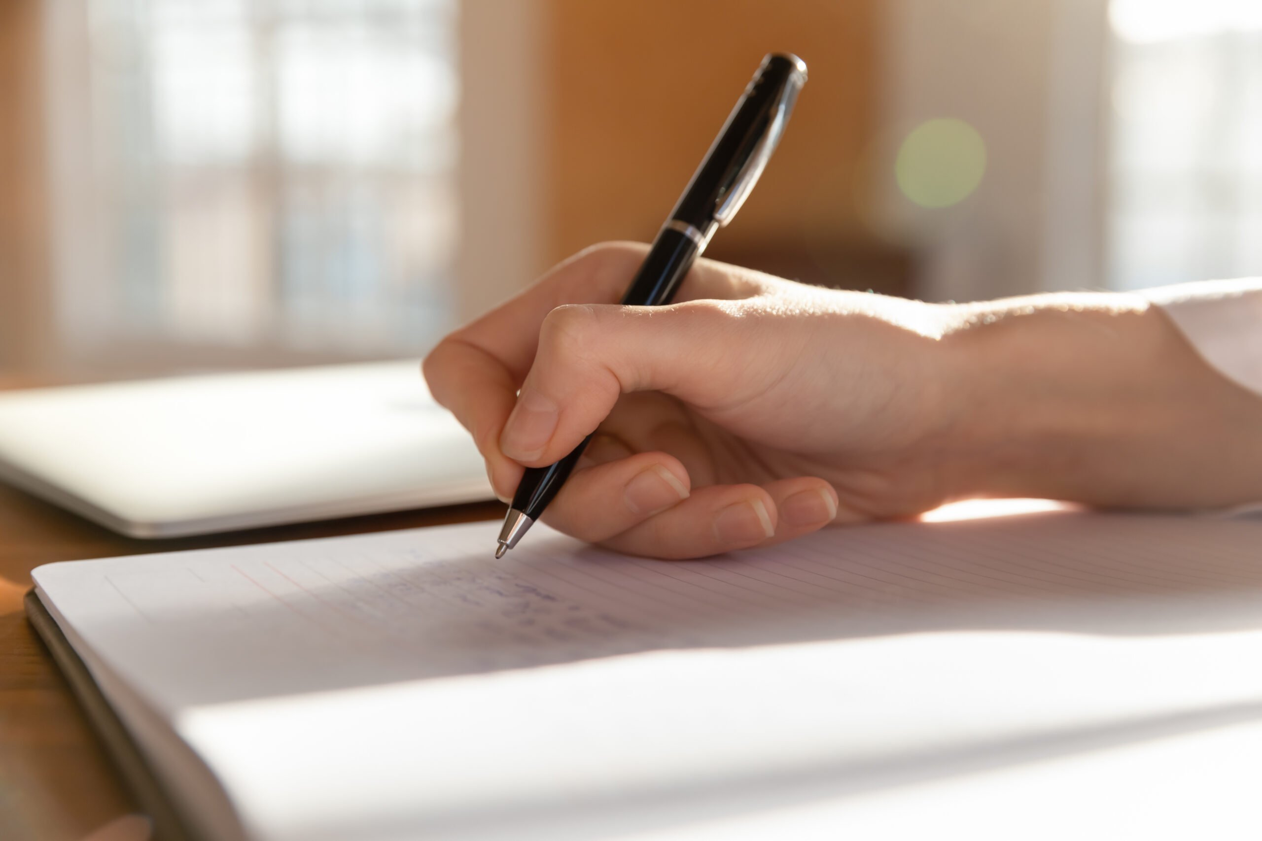 Someone writing in a notebook with a pen.